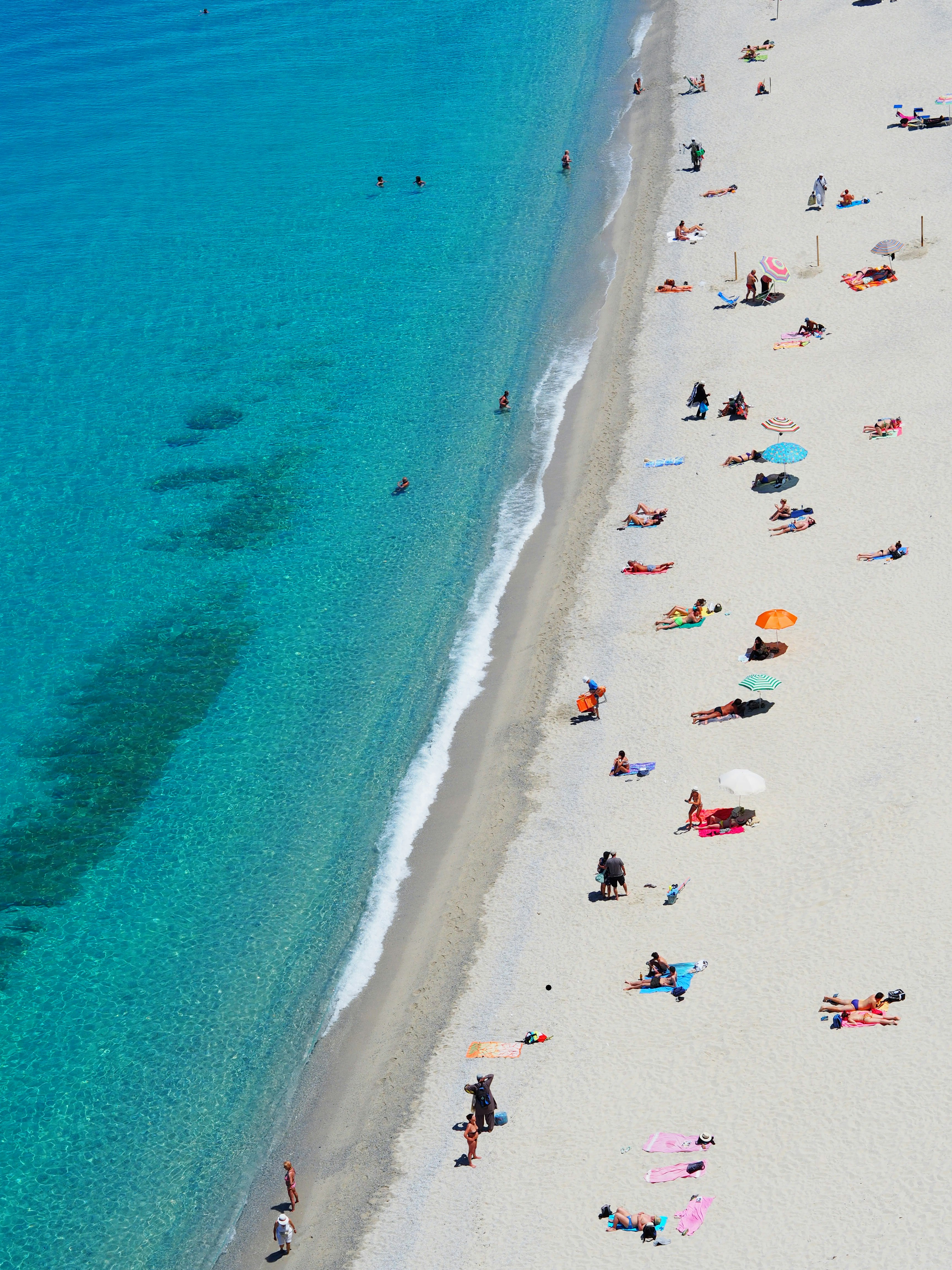 Clear turquoise Zanzibar beach with white sand and travelers relaxing near the shoreline