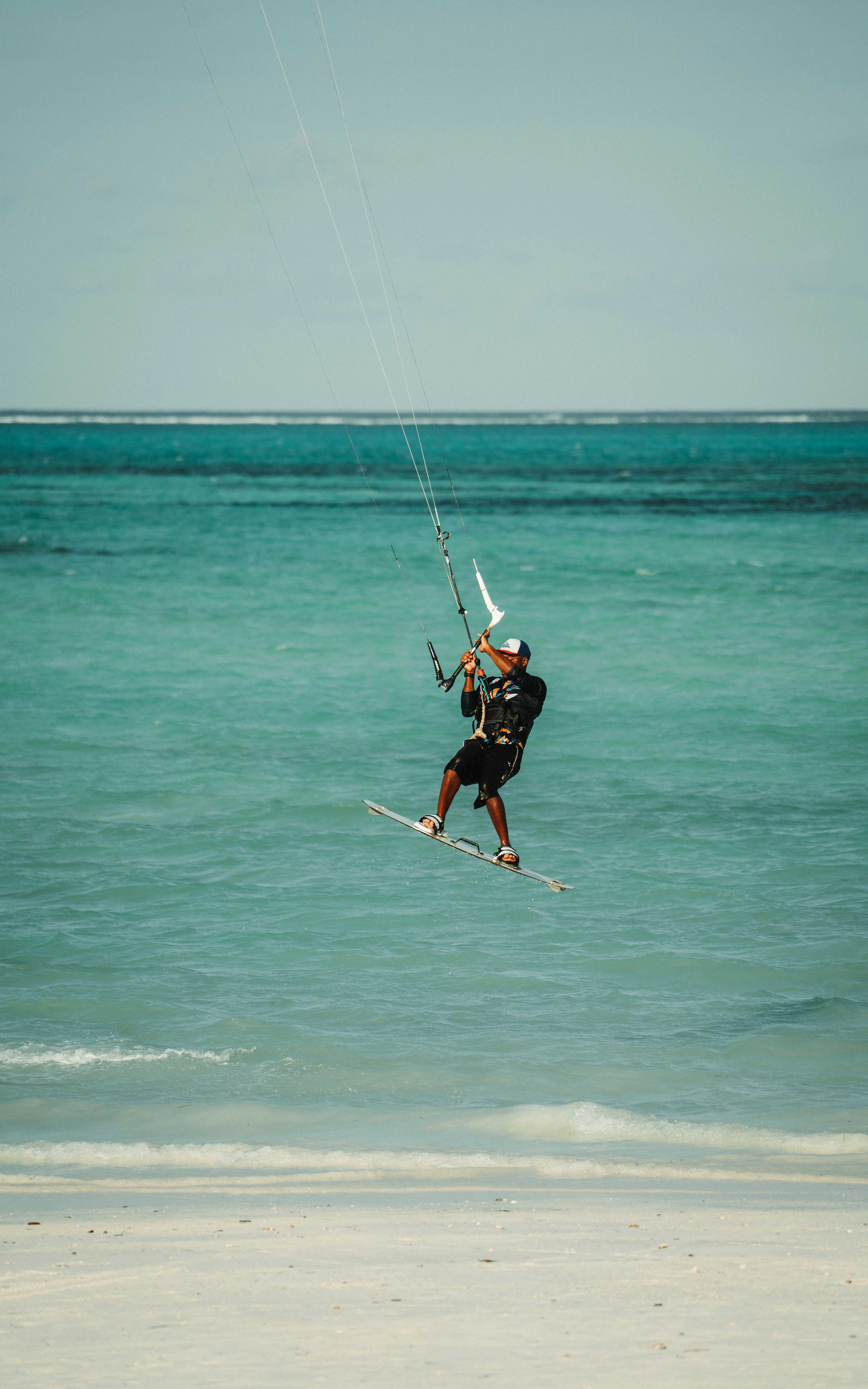 Kitesurfer riding above shallow turquoise water on a Zanzibar beach